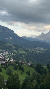Colle Santa Lucia village in the Italian Dolomites with green alpine meadow and mountain backdrop, Italy