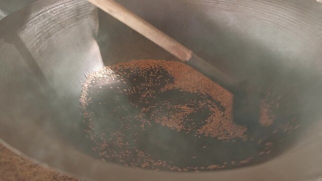 Close up of rice grains being roasted in a large, steaming wok