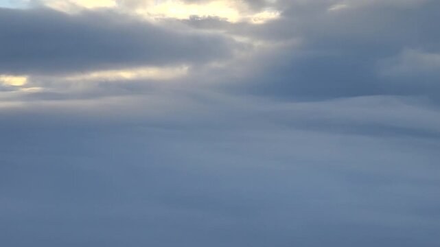 Aerial view of sunbeams breaking through thick dark clouds from high altitude.