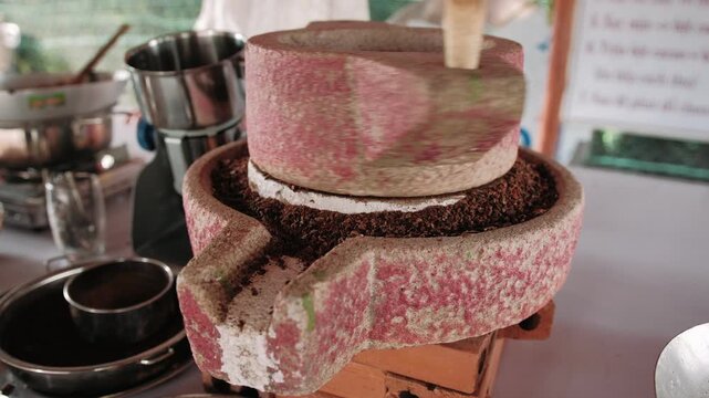Grinding cacao nibs into chocolate in traditional stone mill an authentic vietnamese workshop
