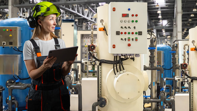 Water treatment plant, female technician checks control panel and industrial filtration equipment using tablet in processing facility.