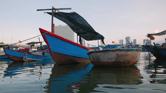 Traditional vietnam fishing boats and round basket boat moored in Nha Trang harbor reflecting on the water