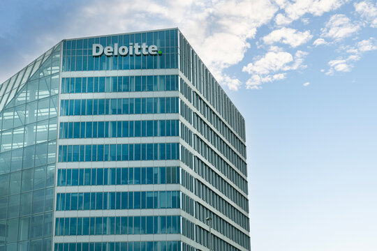 Netherlands - April 17, 2026: The modern glass exterior of "The Edge" building, Deloitte's headquarters in Amsterdam, showcased against a blue sky with light clouds.