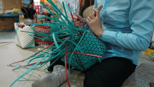 Woman weaving plastic basket in a workshop, showcasing handmade craft and cultural heritage, Vietnam