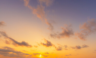 Fototapeta premium Golden Hour Sunset Sky with Soft Pastel Clouds and Warm Sunlight,A breathtaking view of the evening sky during sunset, featuring a vibrant blend of orange, yellow, and purple hues with soft, scattered