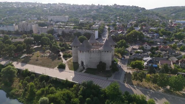 Breathtaking aerial view of the medieval Soroca Fortress in Moldova. Cinematic drone shot of the circular stone castle on the banks of the Dniester River with a cityscape background.