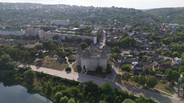 Cinematic aerial view of the medieval Soroca Fortress in Moldova. Drone shot of the circular stone castle on the banks of the Dniester River with park and cityscape in the background.