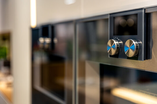 Built-in oven details with metallic knobs. Modern kitchen appliances in interior.