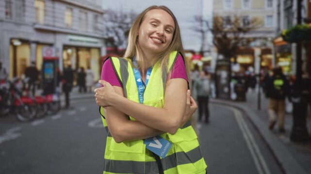 Woman hugging her arms wearing a volunteer badge and reflective vest on a street; community warmth contentment.