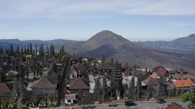 Aerial view of the Pura Ulun Danu Batur temple complex with traditional meru towers and residential houses near the volcanic Mount Batur in Batur, Central Java, Indonesia.