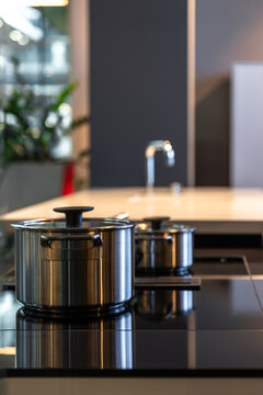 Stainless steel pot on a black induction cooktop. Modern kitchen space design.