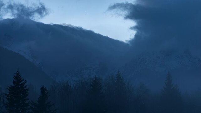 nuvole che cambiamo, si rigenerano, si spostano e si dissolvono sopra le cime di alcune montagne nel nord Italia, dopo il tramonto, in inverno