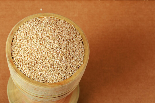 Quinoa seeds (Chenopodium quinoa) in wooden bowl on rustic surface, close-up healthy food composition