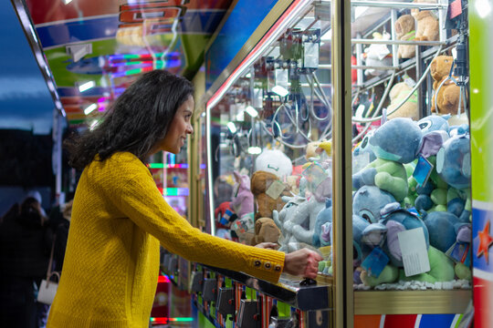 Young Latina woman trying to win plush toy in claw machine