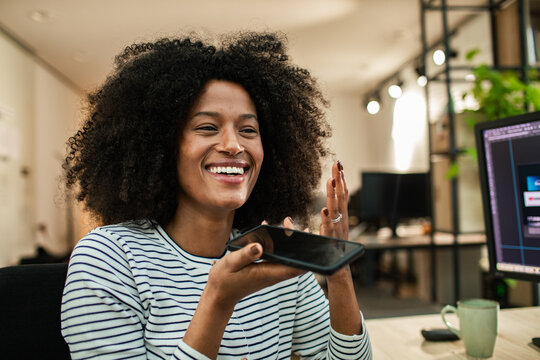 Smiling woman using voice command at office desk