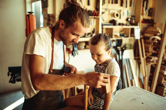 Father teaching daughter woodworking in home workshop