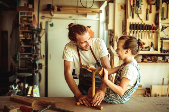 Father teaching daughter woodworking in home workshop