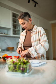 Mature adult chopping fresh vegetables in home kitchen