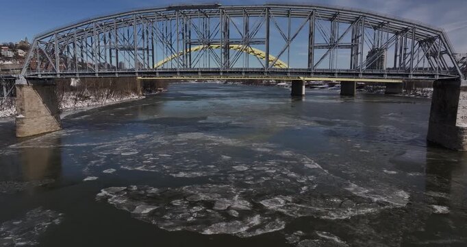 Aerial view of the Ohio River filled with floating ice chunks flowing under the historic steel truss CO Bridge and the yellow Daniel Carter Beard Bridge in Cincinnati, Ohio, United States.