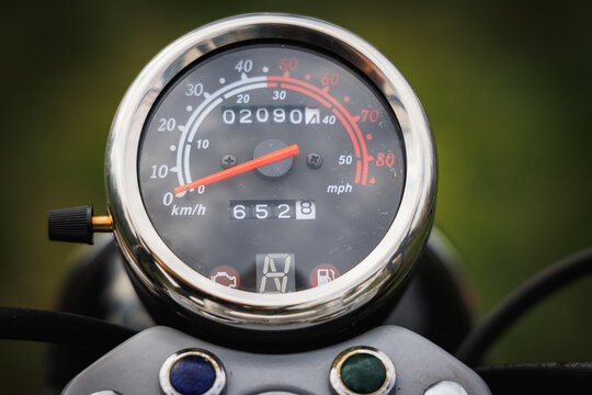 Close up of a chrome motorcycle speedometer with odometer and red needle