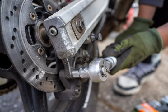 Mechanic adjusts wheel. Professional technician carefully tightening axle in brake assembly area