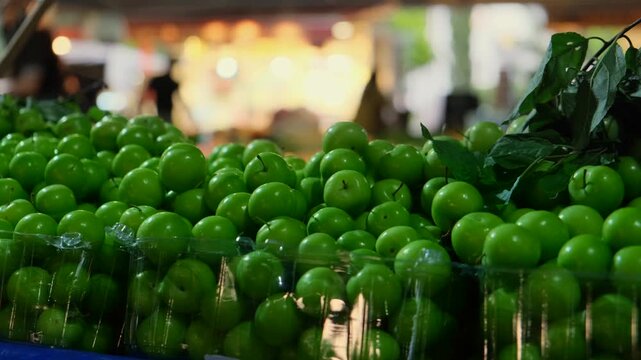 Fresh green plums at busy Turkish street market, seasonal spring fruit, authentic bazaar atmosphere, local produce and realistic everyday shopping lifestyle