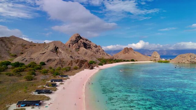 Aerial view of the famous Pink Beach with turquoise water and rugged hills in Komodo National Park, East Nusa Tenggara, Indonesia.