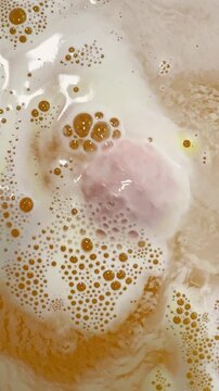 Yellow bath bomb spins and fizzes bubbles in bathtub water