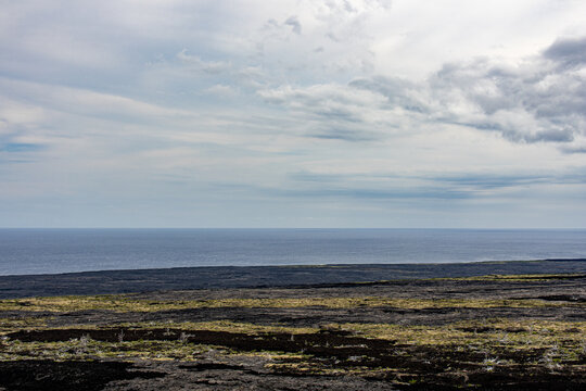 High angle view of a vast black lava field meeting the blue Pacific Ocean at Hawaii Volcanoes National Park Big Island Hawaii