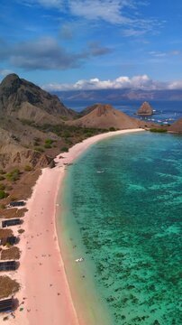 Aerial view of the famous Pink Beach with turquoise waters and rugged hills in Komodo National Park, East Nusa Tenggara, Indonesia.