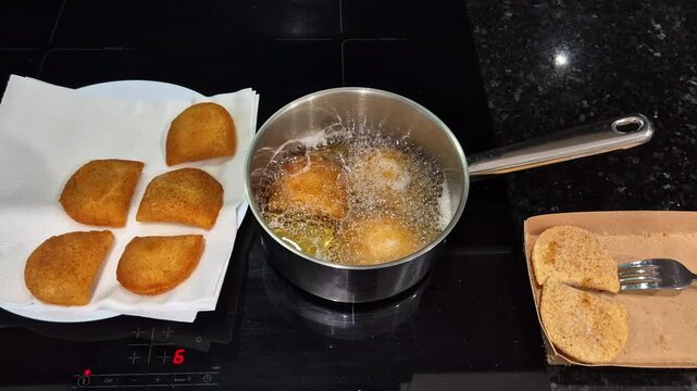 Portuguese rissois being fried in hot oil, a traditional appetizer cooking in a kitchen.