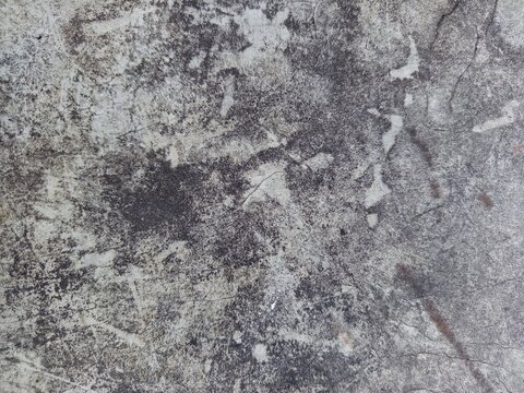 Top view close-up of a rustic dirt ground surface mixed with coarse sand, scattered white limestone pebbles, broken gravel, and small patches of wild green grass.