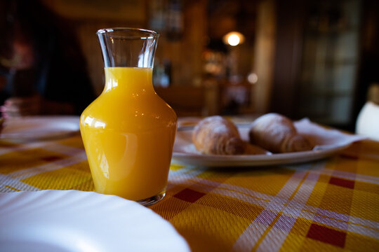 caraffa con spremuta di aranciata fresca, su un tavolo, durante la colazione, vicino ad un piatto con delle brioche