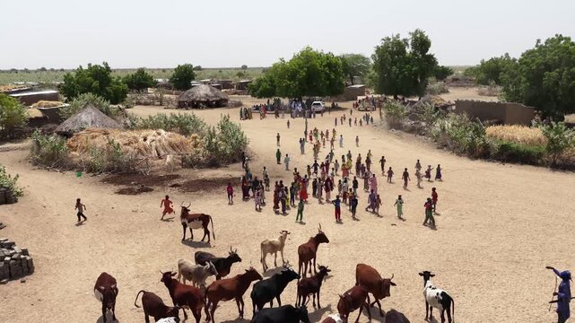 Drone view of village children running after the drone on dusty road, April 25, 2026, Chad, N Djamena