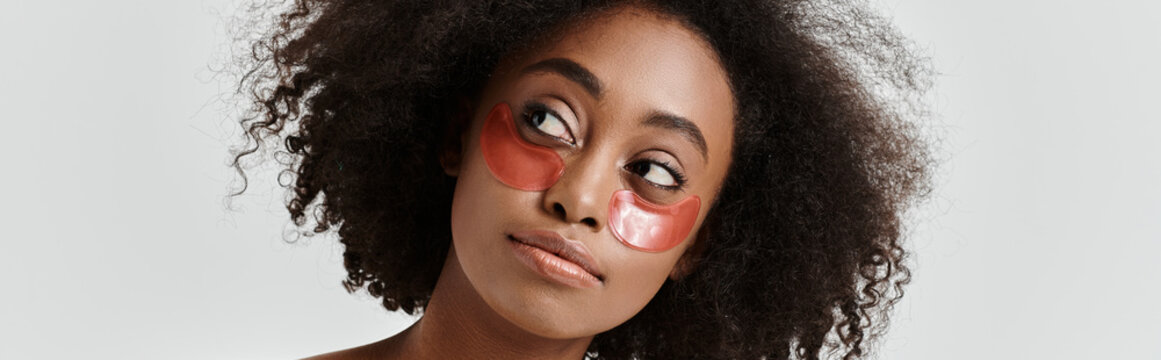 Young woman with curly hair embracing beauty rituals in a serene studio setting
