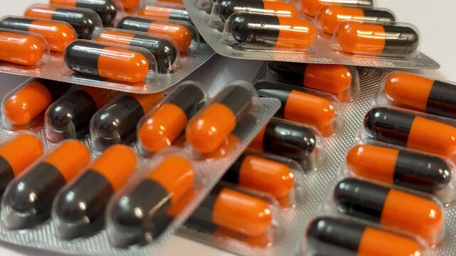 Orange And Black Capsules In Blister Pack, Closeup Showing Glossy Capsules Arranged In Foil Trays, Pharmacy Storage And Packaging Scene With Emphasis On Dosage, Sterile Clinical Lighting