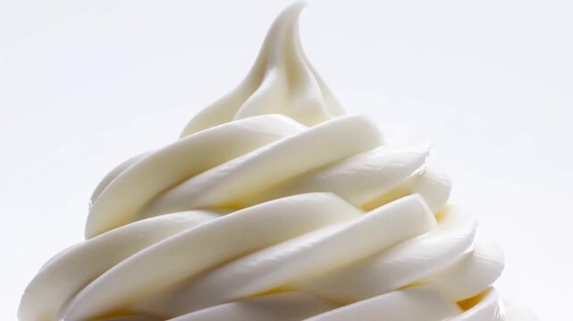 Slow motion tracking shot of soft serve ice cream swirl rotating on white studio background