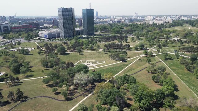 Aerial pull-back shot from a drone revealing the expansive greenery of Usce Park in New Belgrade, Serbia.