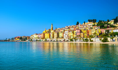 Menton, a colorful Mediterranean coastal town with historic buildings, a palm-lined promenade and calm, blue waters. © Lichtwolke99