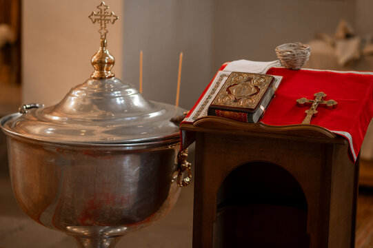Orthodox baptismal font with closed lid and holy bible on analogion table in church