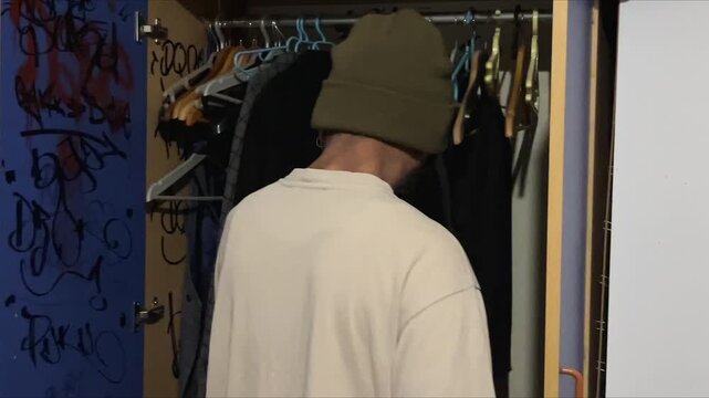 Man Facing Graffiti Chaos in Disordered Closet, Symbolizing Borderline Personality Turmoil and Depressive Identity Struggle
