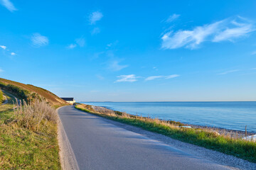 Obraz premium Landscape, mountain road and sky at seaside in summer, asphalt and highway with environment in nature. Outdoor, horizon and space with motorway, transport and infrastructure for travel by ocean