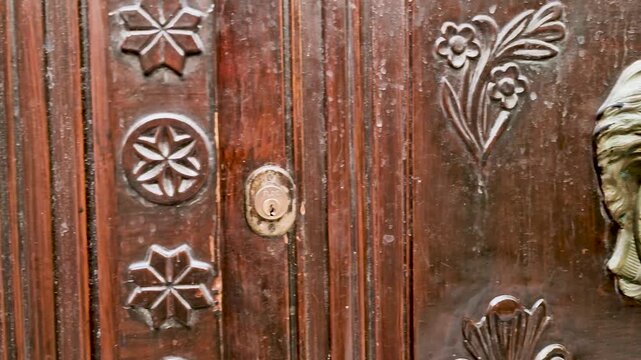 Bronze lion door knob and eagle detail on old Venetian door in Rethymno, Crete. 4k video of ancient historic architecture in Greece. Authentic Mediterranean street aesthetic, rustic stone texture.