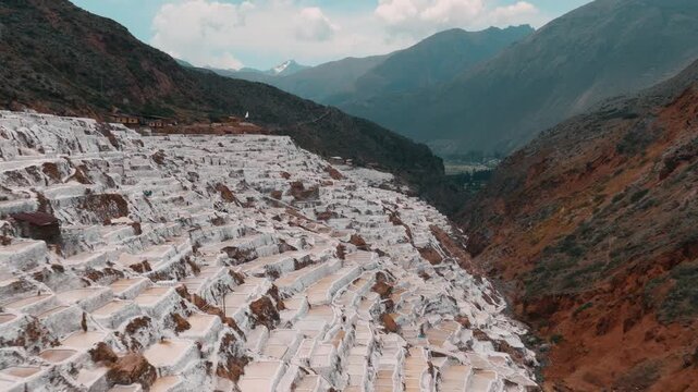 Drone aerial view of the historic Maras Salt Mines near Cusco, Peru. Thousands of terraced salt evaporation ponds cover the mountainside, creating a striking geometric pattern in the heart of the Sacr