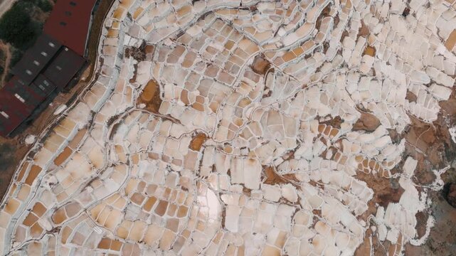 Drone aerial view of the historic Maras Salt Mines near Cusco, Peru. Thousands of terraced salt evaporation ponds cover the mountainside, creating a striking geometric pattern in the heart of the Sacr