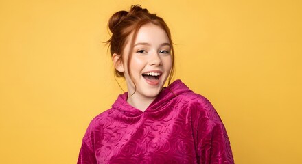 Fototapeta premium Redheaded woman in magenta hoodie laughing on yellow background. Expressive portrait of happy girl with ginger hair. Casual fashion and lifestyle concept for social media content.