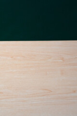 Fototapeta premium Light-colored wooden tabletop with natural grain texture against a deep green background in close-up