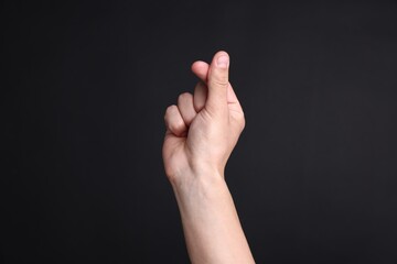 Obraz premium Man showing heart gesture with fingers on black background, closeup
