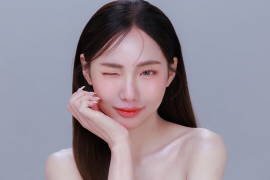 Young Asian Woman with Clean Glowing Skin bright eyes Touching Face for Skincare Concept.