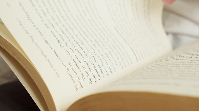 Close-up of hands holding an open book and flipping pages.